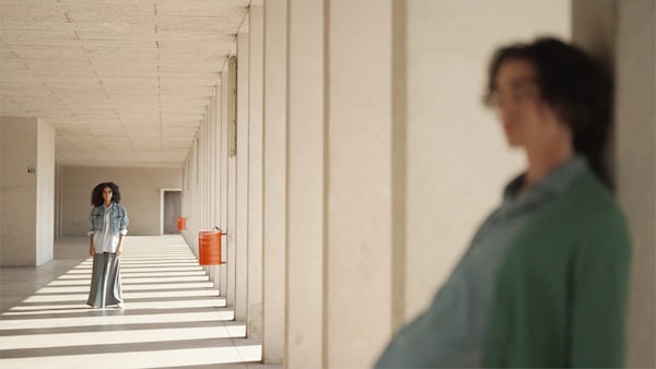 Example image of a woman in the background in focus and a man close to the camera in the foreground out of focus